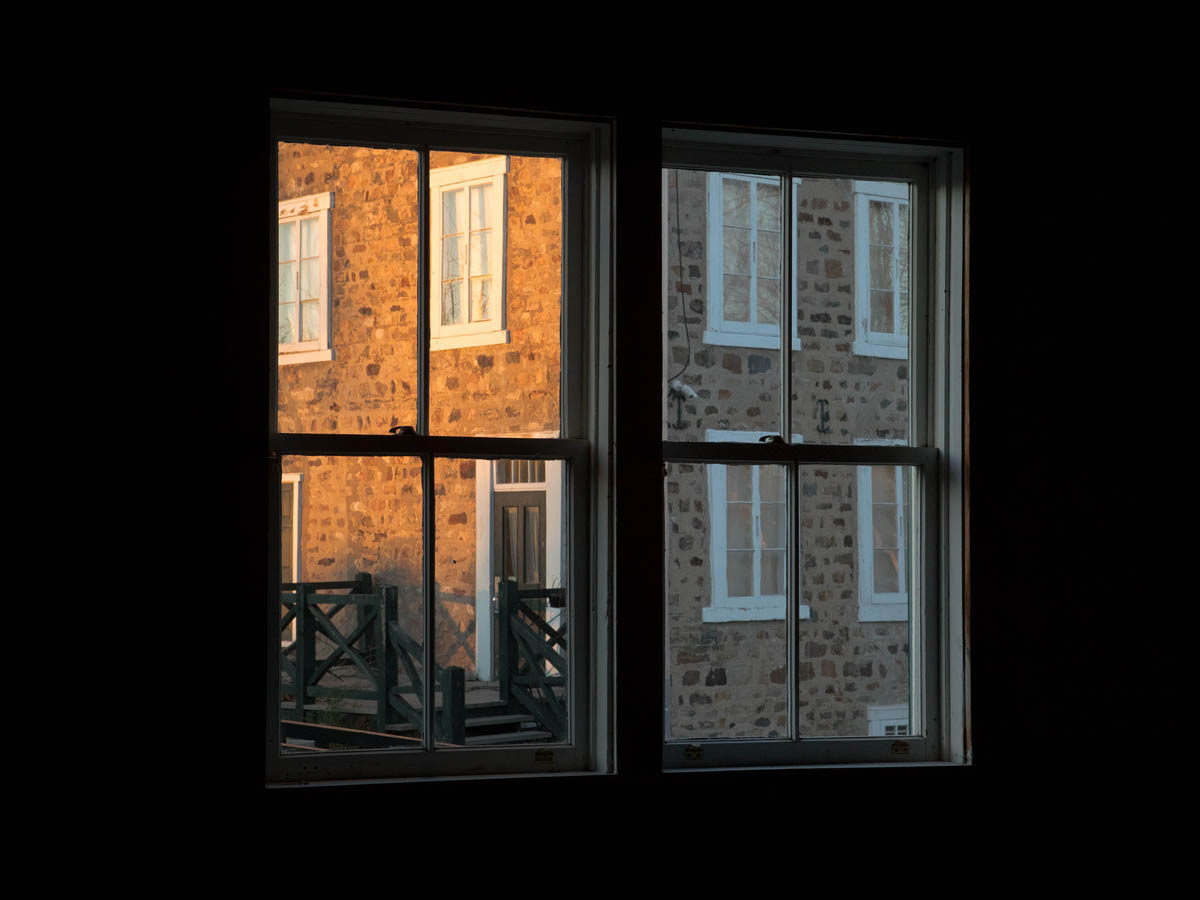 De bois et de pierres : vue sur la maison Jean-Baptiste-Mâsse à travers les fenêtres de la meunerie